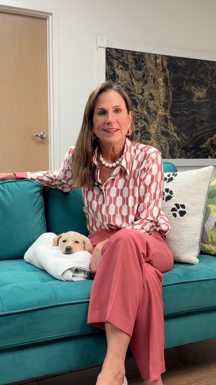 Allison Black Cornelius, CEO of the Greater Birmingham Humane Society, seated on a couch with a yellow lab puppy